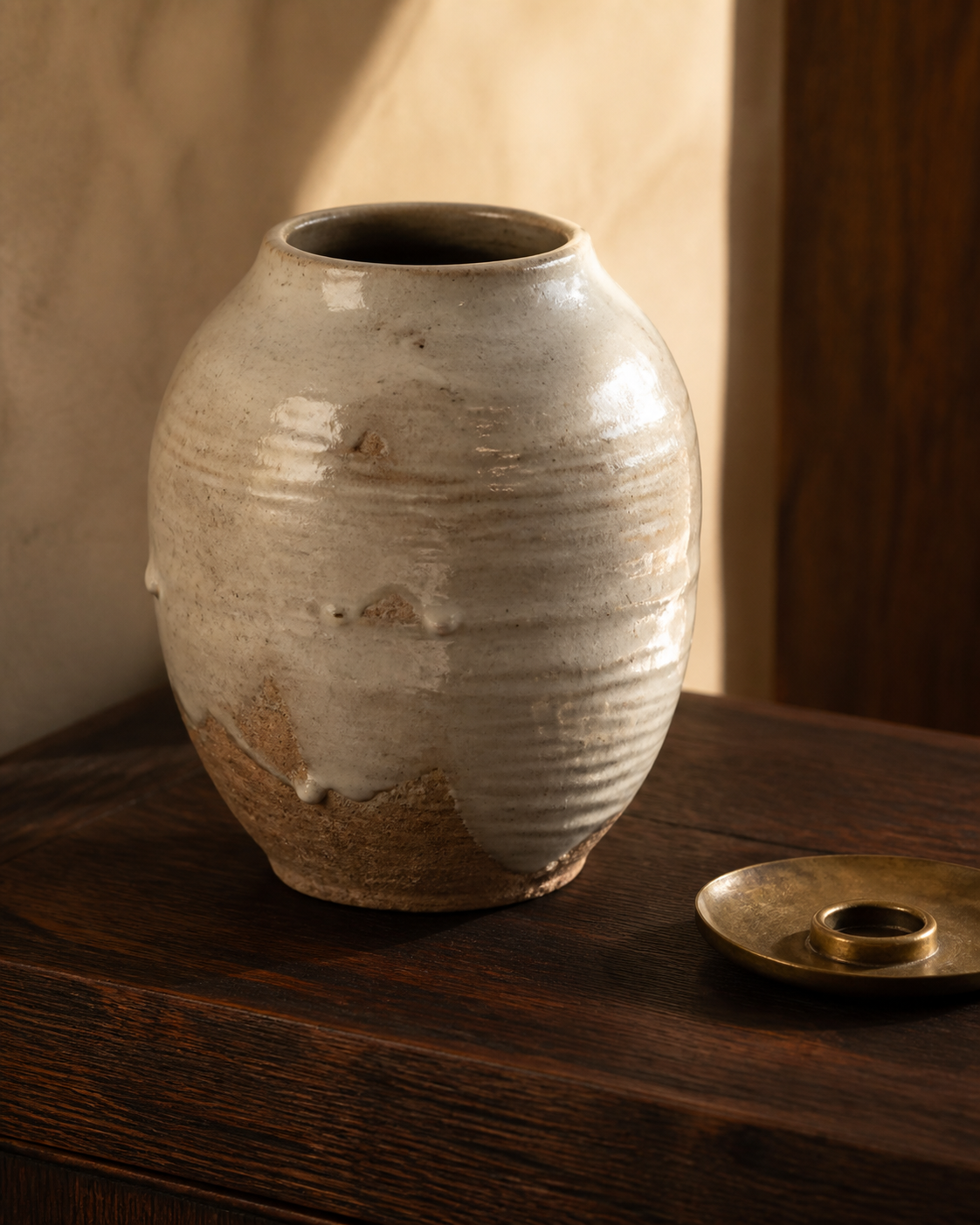 Hand-thrown ceramic vessel beside a turned brass dish